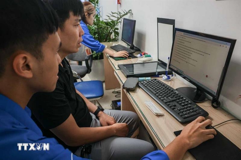 Đoàn viên thanh niên tình nguyện hướng dẫn người dân khai báo trực tuyến làm giấy tờ khai sinh cho con tại điểm phục vụ hành chính công phường Cửa Nam. (Ảnh: Hoàng Hiếu/TTXVN)