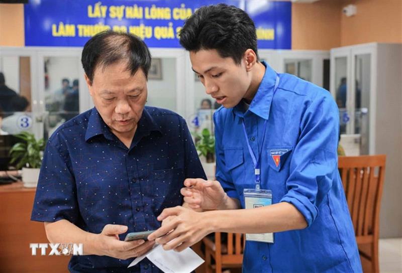 Đoàn viên thanh niên hướng dẫn người dân sử dụng, khai báo, các dịch vụ công trực tuyến trên điện thoại thông minh. (Ảnh: Hoàng Hiếu/TTXVN)