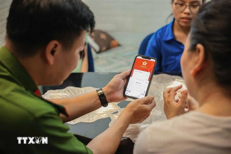 Tổ chuyển đổi số cộng đồng hướng dẫn người dân sử dụng ứng dụng định danh công dân trên môi trường kỹ thuật số (VNeID) có giá trị sử dụng thay thế các giấy tờ truyền thống. (Ảnh: Hoàng Hiếu/TTXVN)