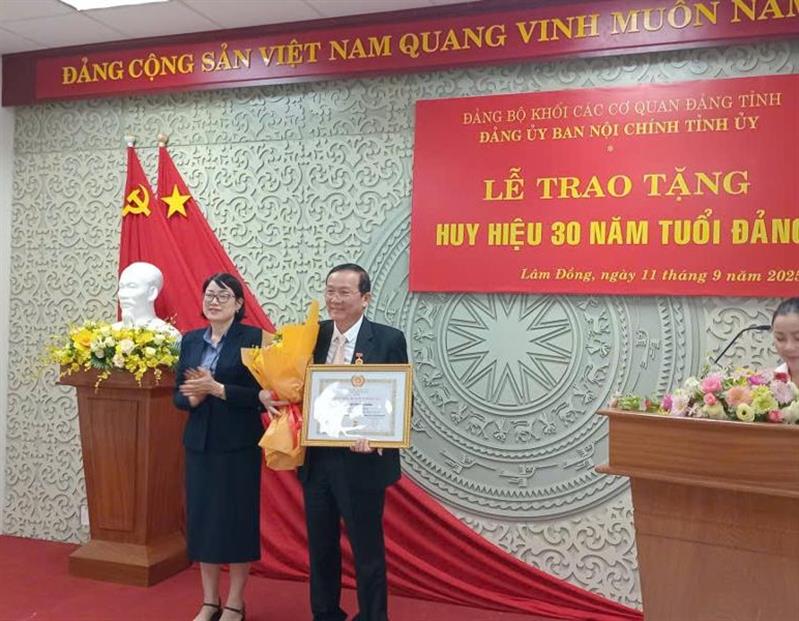 Đồng chí Lê Thị Hải Duyên – Tỉnh ủy viên, Phó Bí thư Đảng ủy các cơ quan Đảng tỉnh trao huy hiệu 30 năm tuổi đảng và tặng hoa cho đồng chí Nguyễn Văn Hoàng