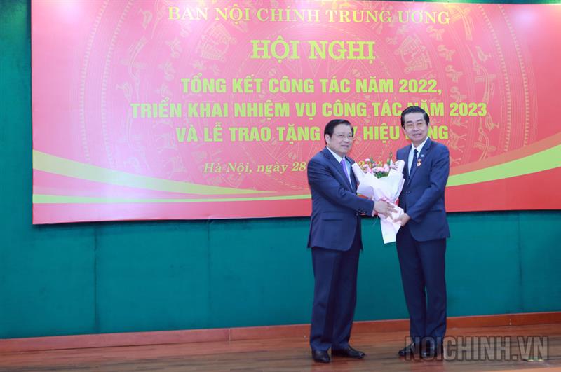 Đồng chí Phan Đình Trạc, Ủy viên Bộ Chính trị, Bí thư Trung ương Đảng, Trưởng Ban Nội chính Trung ương trao Huy hiệu 40 năm tuổi đảng và tặng hoa chúc mừng đồng chí Võ Văn Dũng, Ủy viên Trung ương Đảng, Phó Trưởng ban Thường trực, Bí thư Đảng ủy Cơ quan Ban Nội chính Trung ương